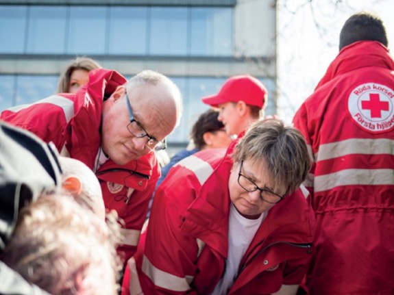 Rödklädd man och kvinna stöttar en person.