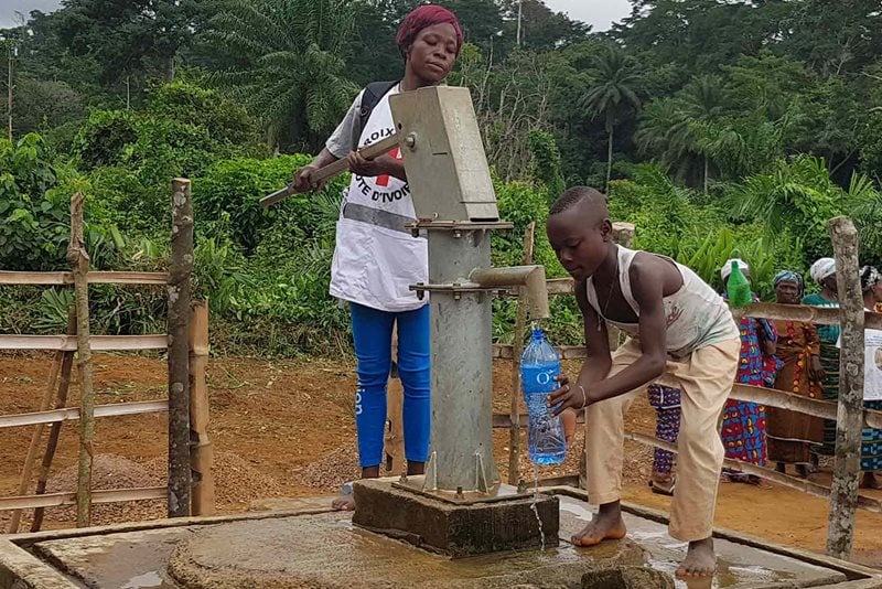 En pojke hämtar rent vatten från vattenpump under ett hälsoprojekt på Elfenbenskusten.