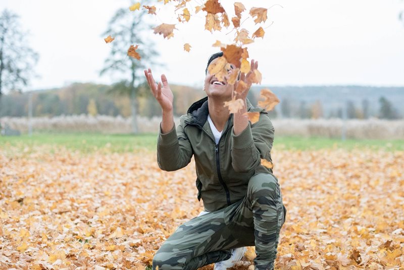 Ungdom som kastar upp löv i luften