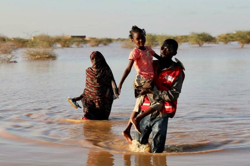 Volontär bär barn genom översvämning, Kartoum Sudan, september 2020.