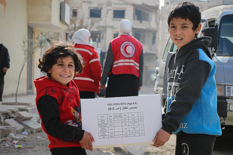 Barn bär paket från Röda Korset - Syrien 2022