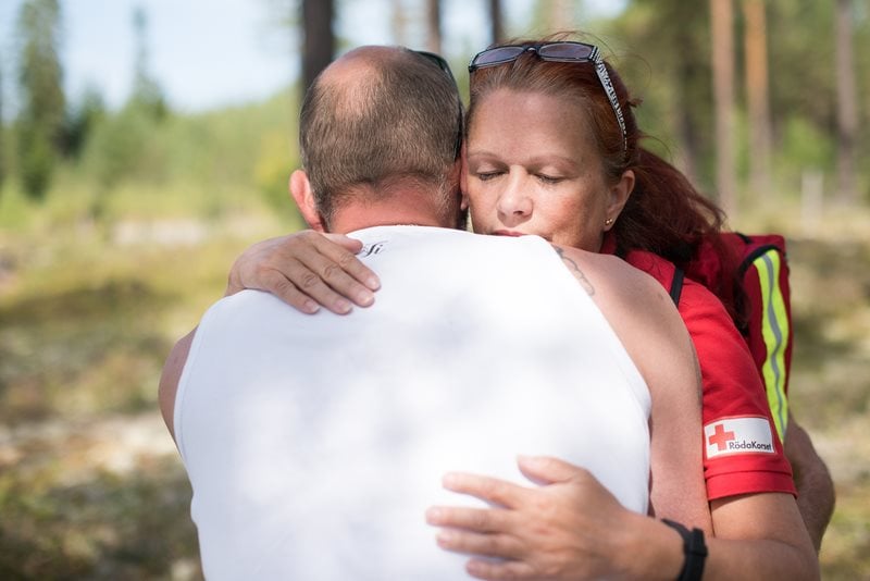 En kvinna/rödakorsare kramar om en person.